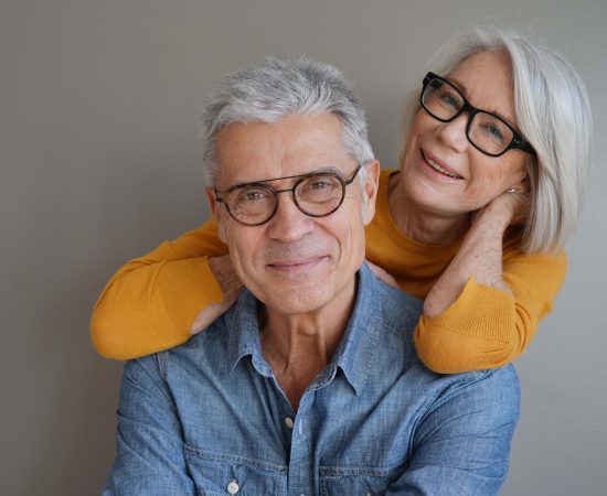 Portrait of relaxed fun senior couple wearing glasses on background